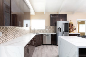 This travertine backsplash breaks up the large blocks of neutral colors with a beautiful diamond frame pattern that ties in the darks of the cabinets to the lights of the countertops.